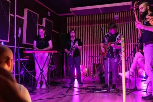 Generic stock atmosphere: musicians jamming on a purple-lit stage, not this event or venue